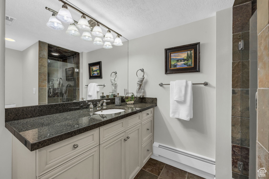 Bathroom featuring a baseboard heating unit, a textured ceiling, an enclosed shower, tile floors, and vanity
