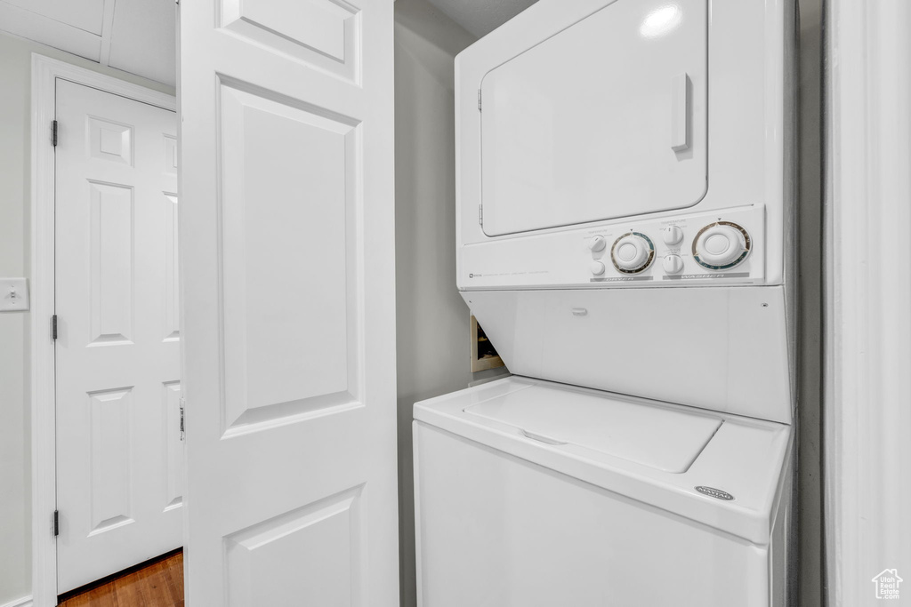 Laundry room featuring hardwood / wood-style floors and stacked washer and clothes dryer