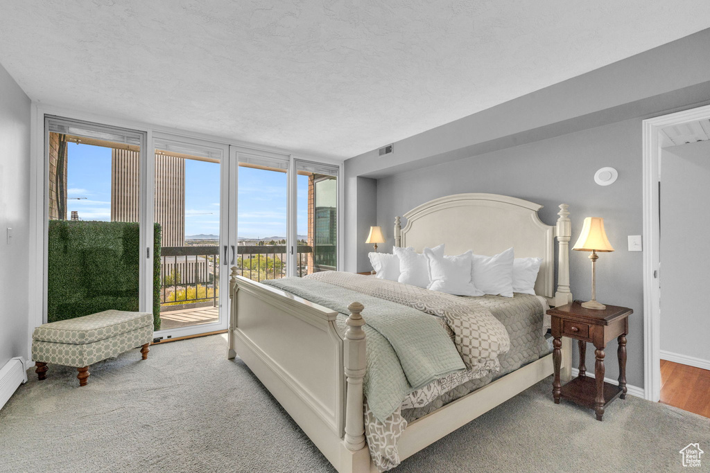 Bedroom featuring expansive windows, a textured ceiling, hardwood / wood-style flooring, and access to outside