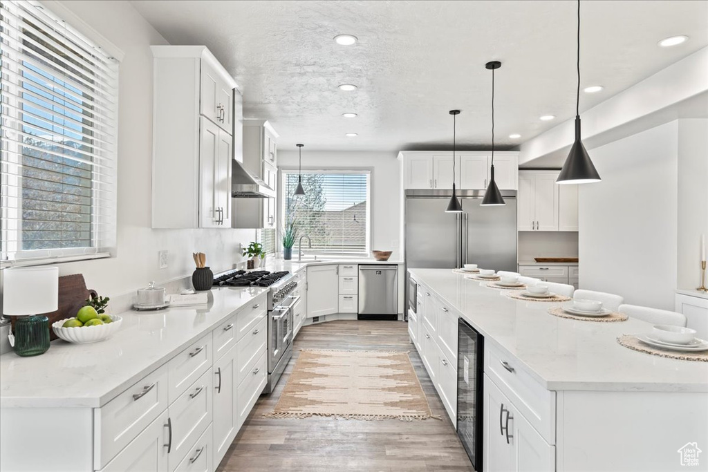 Kitchen featuring a kitchen island, wine cooler, light wood-type flooring, and premium appliances