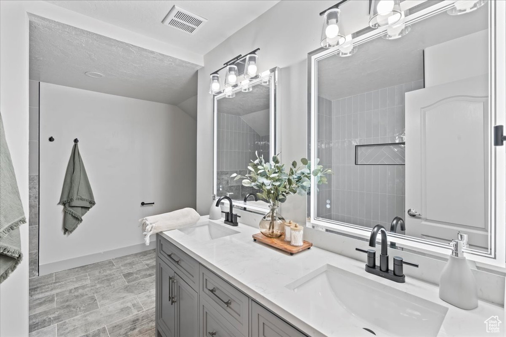 Bathroom with a textured ceiling, tile floors, and double sink vanity