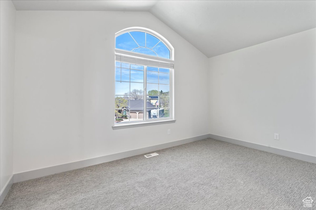 Empty room with carpet flooring and lofted ceiling