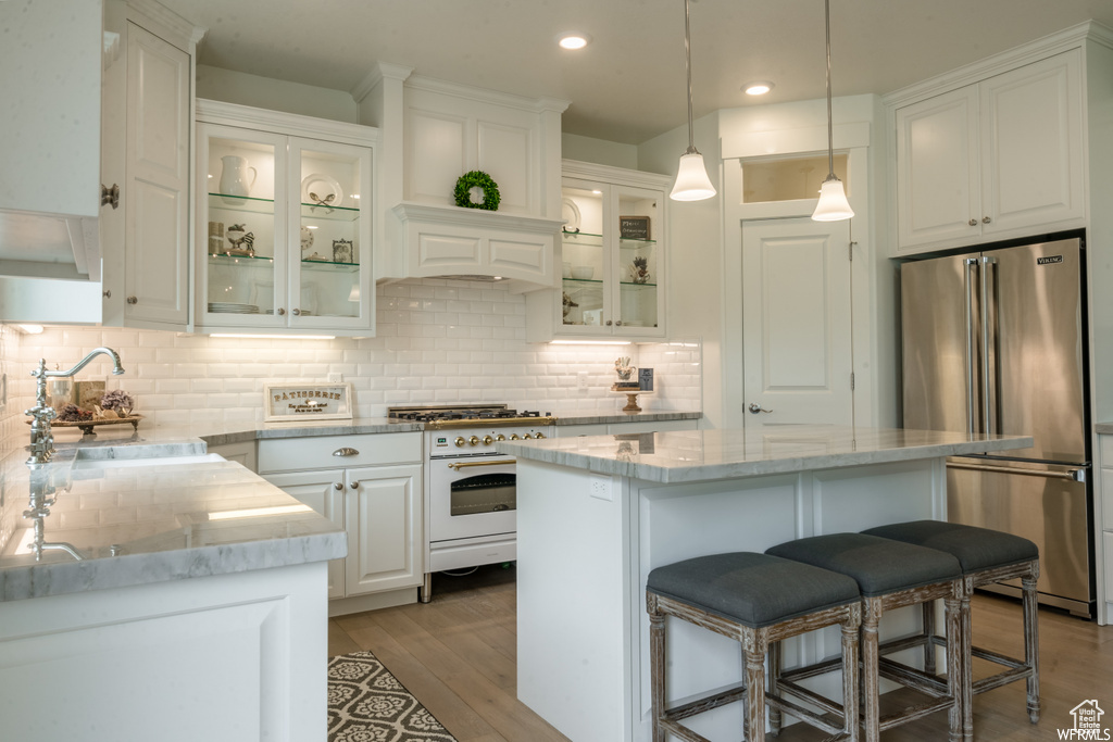Kitchen featuring a center island, tasteful backsplash, white cabinets, and high quality appliances