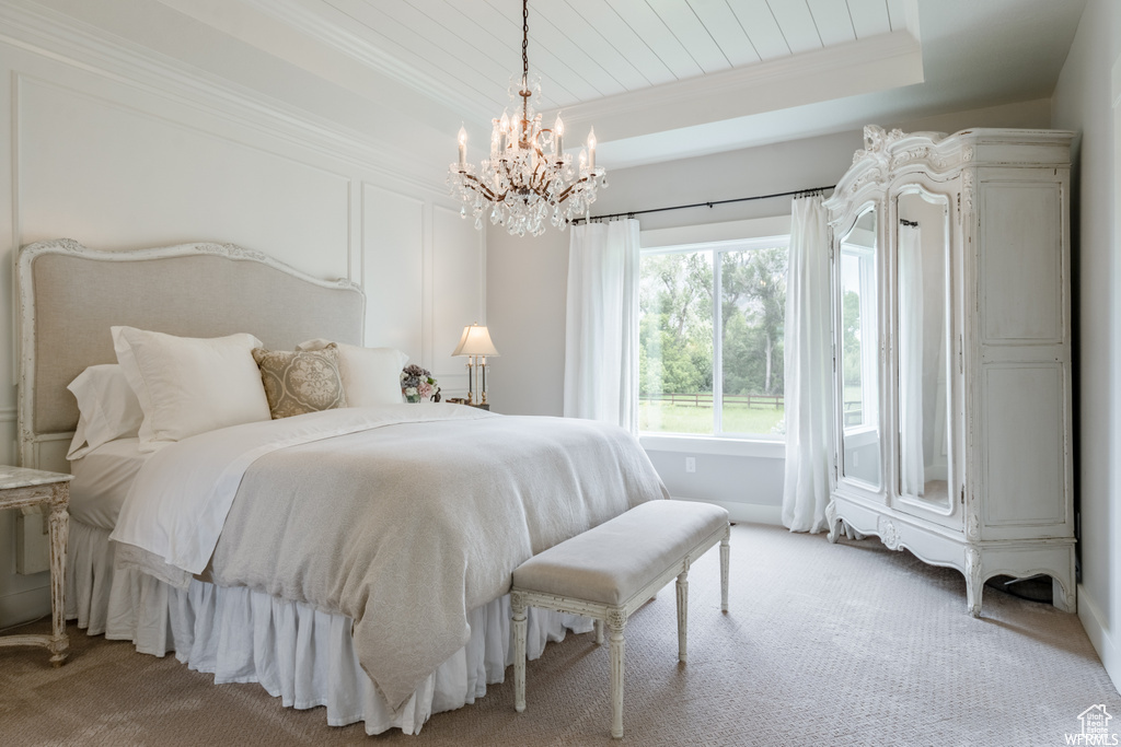 Bedroom with a chandelier, carpet flooring, and a raised ceiling