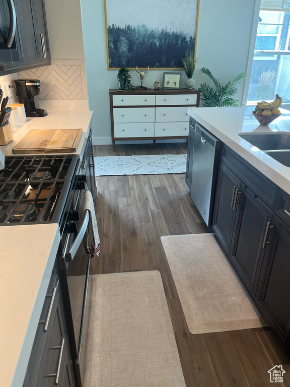 Kitchen with sink, tasteful backsplash, stainless steel appliances, and dark wood-type flooring