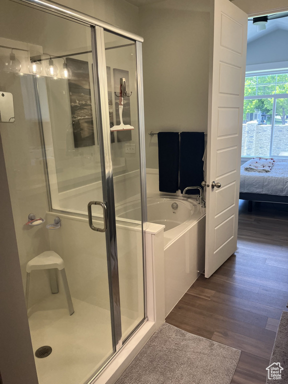 Bathroom with vaulted ceiling, independent shower and bath, and hardwood / wood-style floors