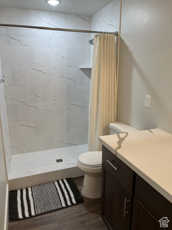 Bathroom with walk in shower, hardwood / wood-style floors, and toilet