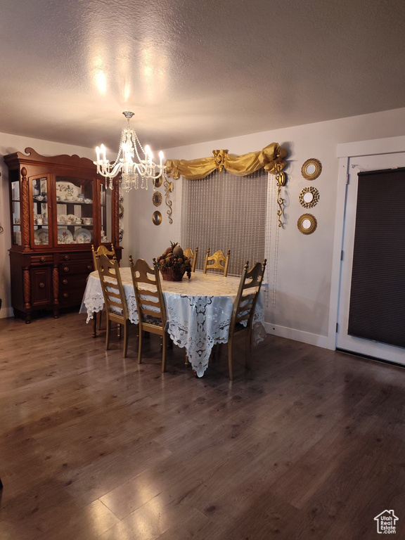 Dining room featuring an inviting chandelier, dark wood-type flooring, and a textured ceiling