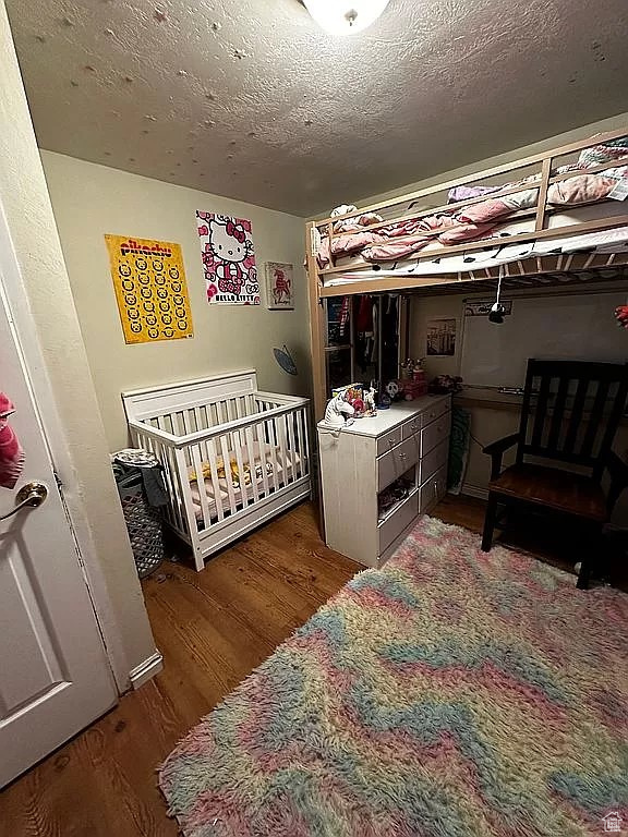 Bedroom featuring a crib and dark hardwood / wood-style floors