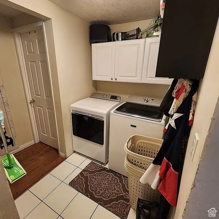 Laundry room featuring cabinets, light tile flooring, and washer and dryer