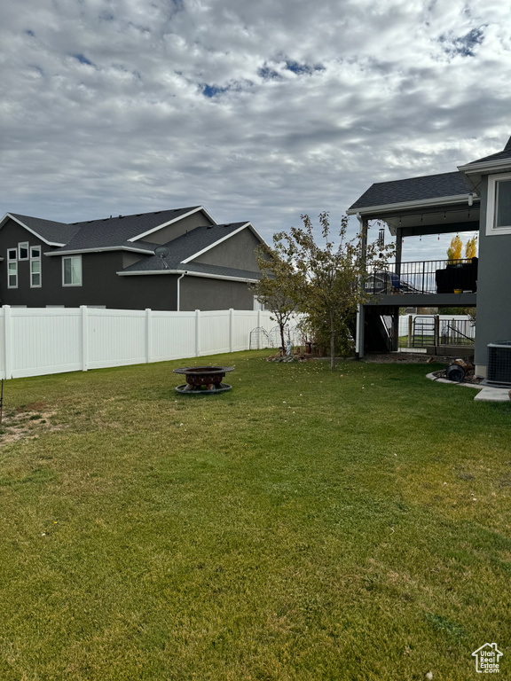 View of yard with central air condition unit, a deck, and an outdoor fire pit