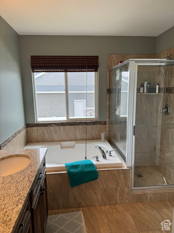 Bathroom featuring vanity, shower with separate bathtub, and tile flooring