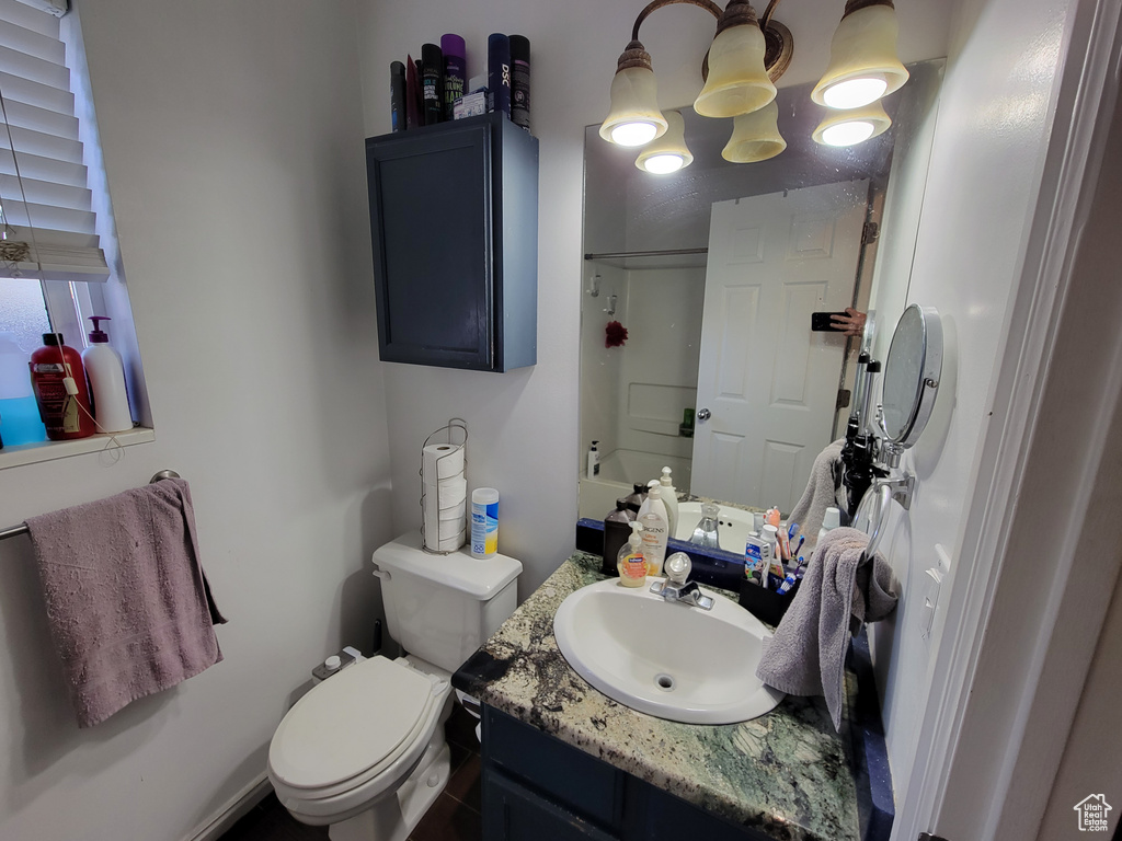 Bathroom with vanity, an inviting chandelier, and toilet