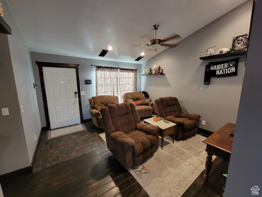 Living room with dark hardwood / wood-style floors, ceiling fan, and lofted ceiling