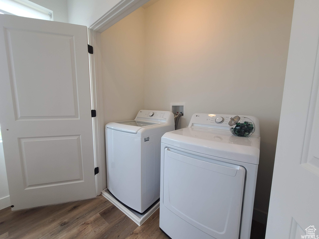 Laundry area with dark wood-type flooring, hookup for a washing machine, and washing machine and clothes dryer
