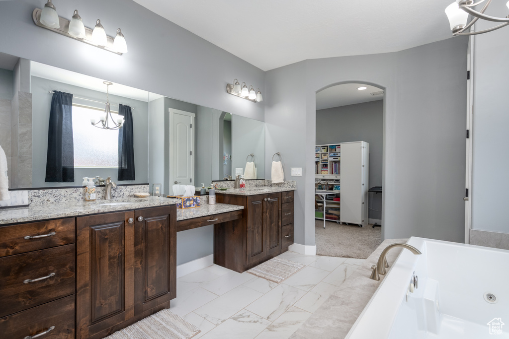 Bathroom with a notable chandelier, vanity, tile floors, and a bathtub