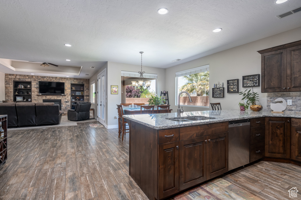 Kitchen featuring hardwood / wood-style flooring, a fireplace, sink, a raised ceiling, and stainless steel dishwasher