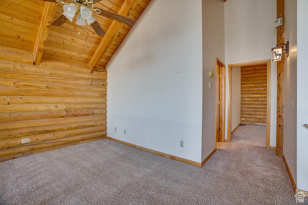 Additional living space with log walls, ceiling fan, wood ceiling, beam ceiling, and carpet flooring