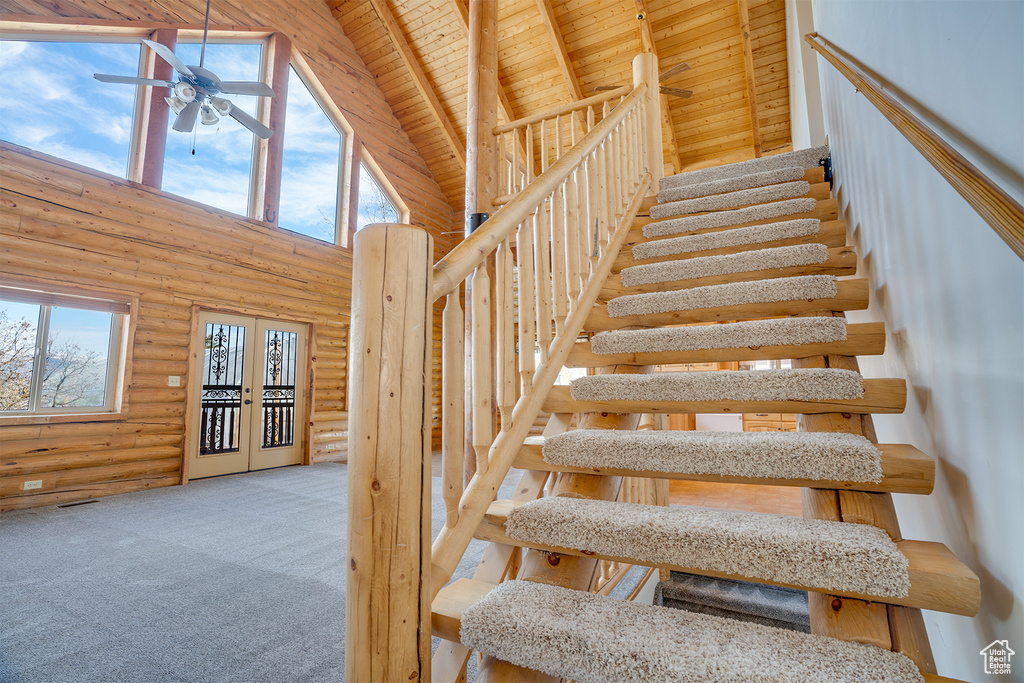 Stairs featuring wood ceiling, a healthy amount of sunlight, carpet, and high vaulted ceiling