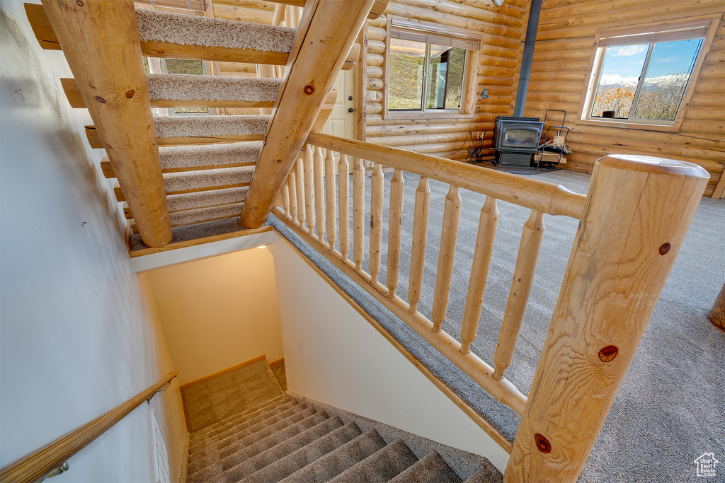 Stairs with carpet flooring, a wood stove, and rustic walls
