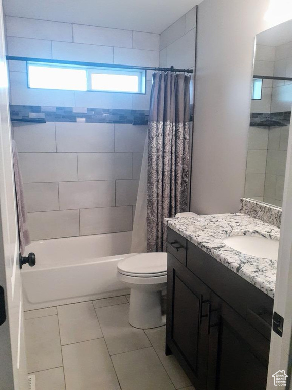 Full bathroom with vanity with extensive cabinet space, shower / tub combo, toilet, and tile flooring