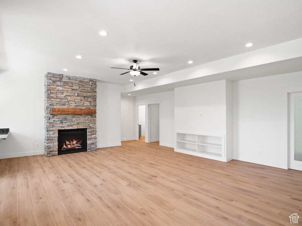 Unfurnished living room featuring light hardwood / wood-style floors, ceiling fan, and a fireplace