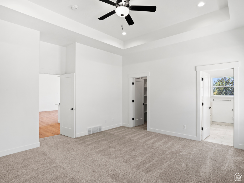 Carpeted spare room featuring ceiling fan and a tray ceiling