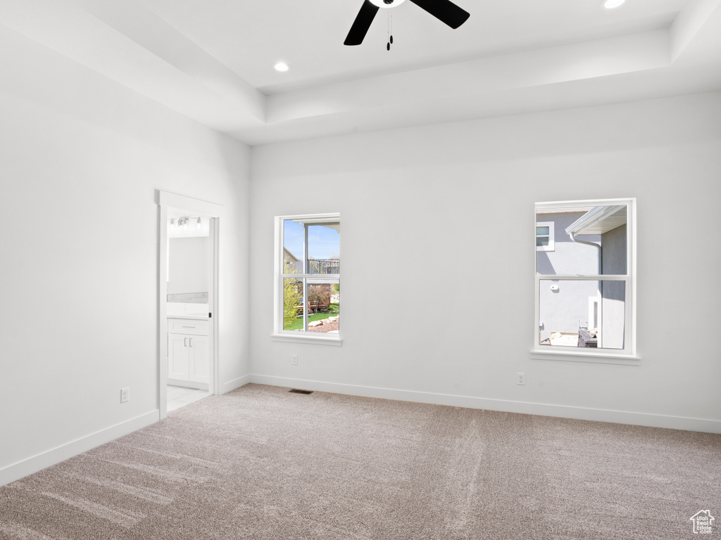Unfurnished room with a raised ceiling, ceiling fan, and carpet