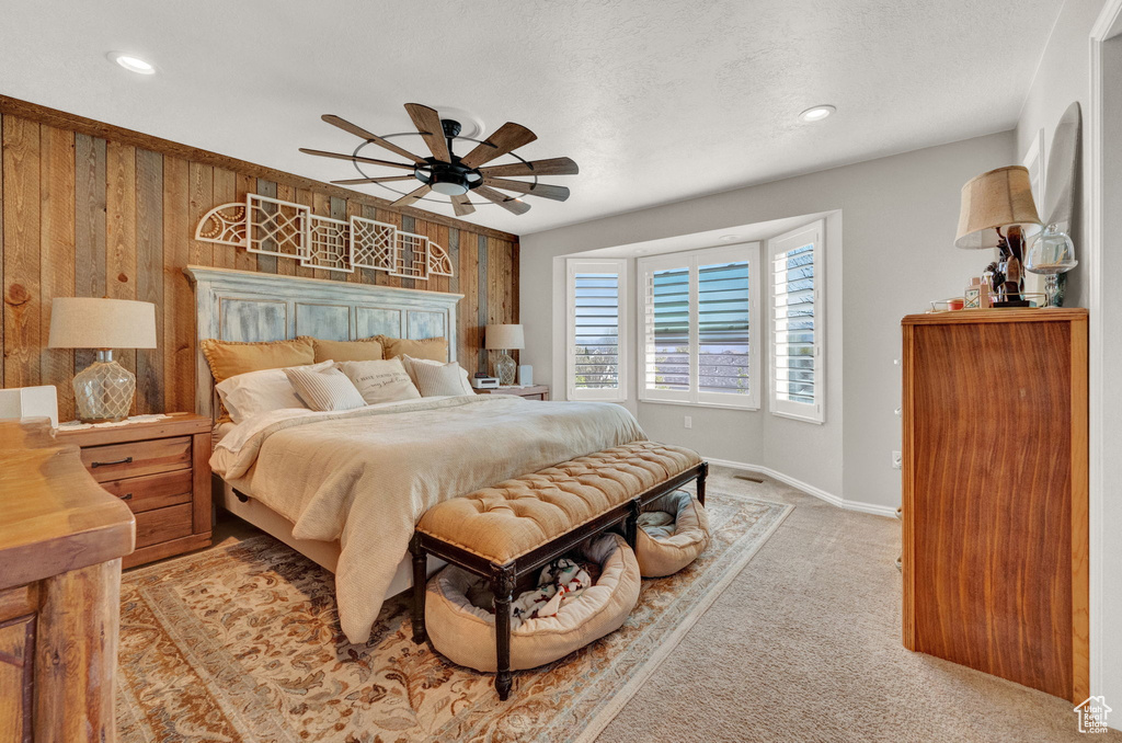 Bedroom featuring ceiling fan, carpet, and wooden walls