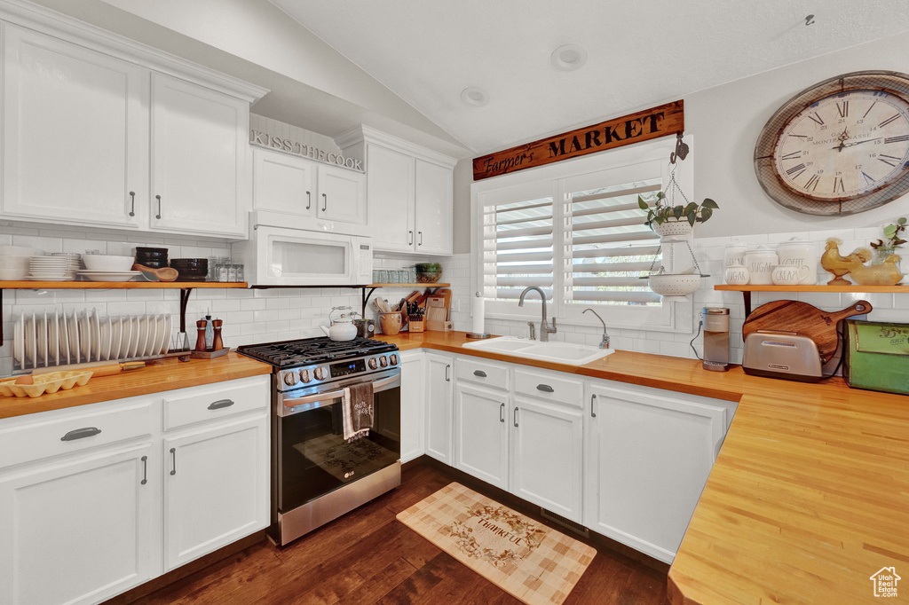 Kitchen featuring sink, white cabinetry, stainless steel gas stove, lofted ceiling, and dark hardwood / wood-style floors