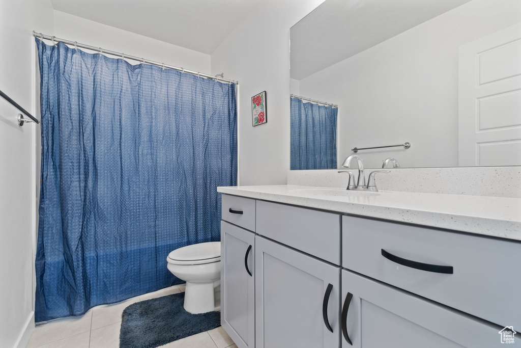 Bathroom featuring tile flooring, toilet, and large vanity