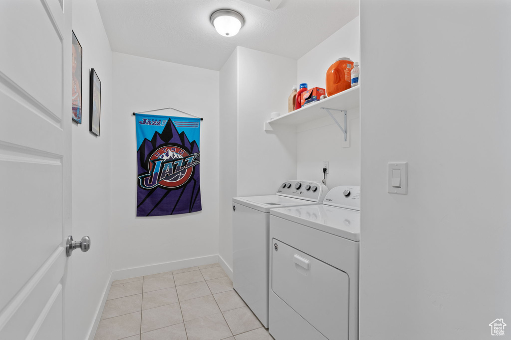 Clothes washing area with light tile floors and washer and clothes dryer