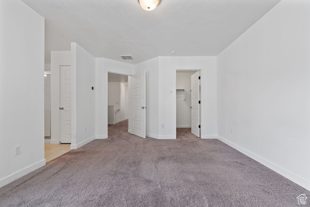 Unfurnished bedroom with a closet, a spacious closet, and light carpet