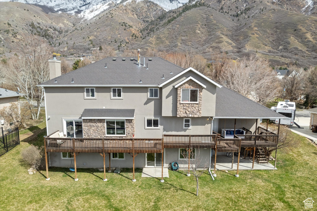 Back of property featuring a yard and a deck with mountain view