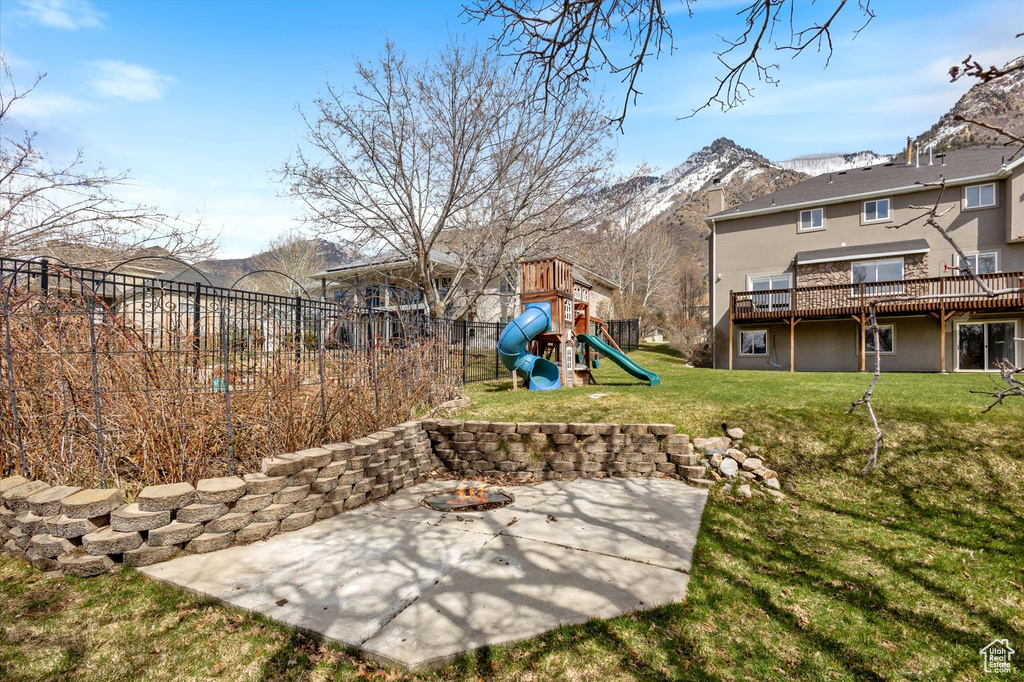 View of yard featuring a patio, a playground, and a deck with mountain view