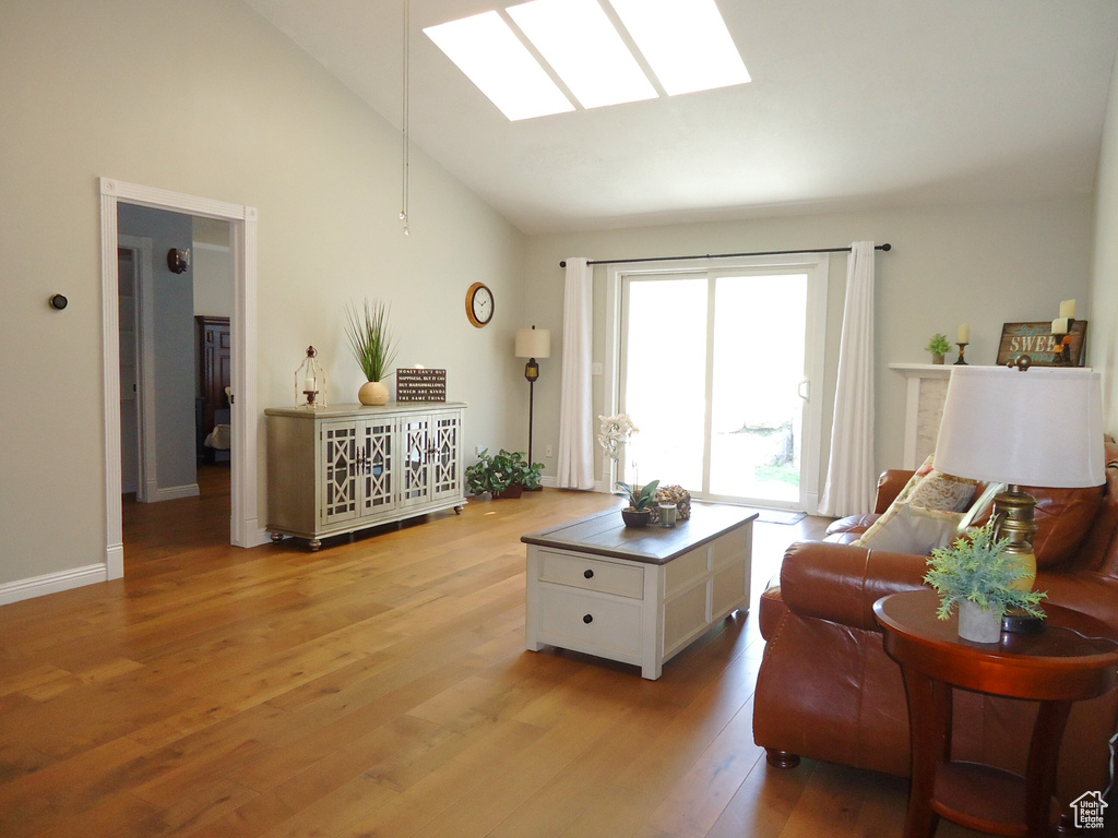Living room featuring a skylight, light hardwood / wood-style floors, and high vaulted ceiling