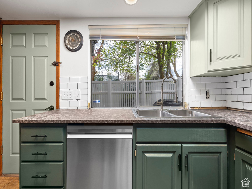 Kitchen featuring tasteful backsplash, dishwasher, green cabinetry, and sink