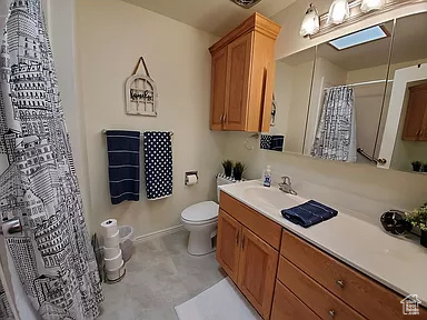 Bathroom with vanity with extensive cabinet space, toilet, and tile floors