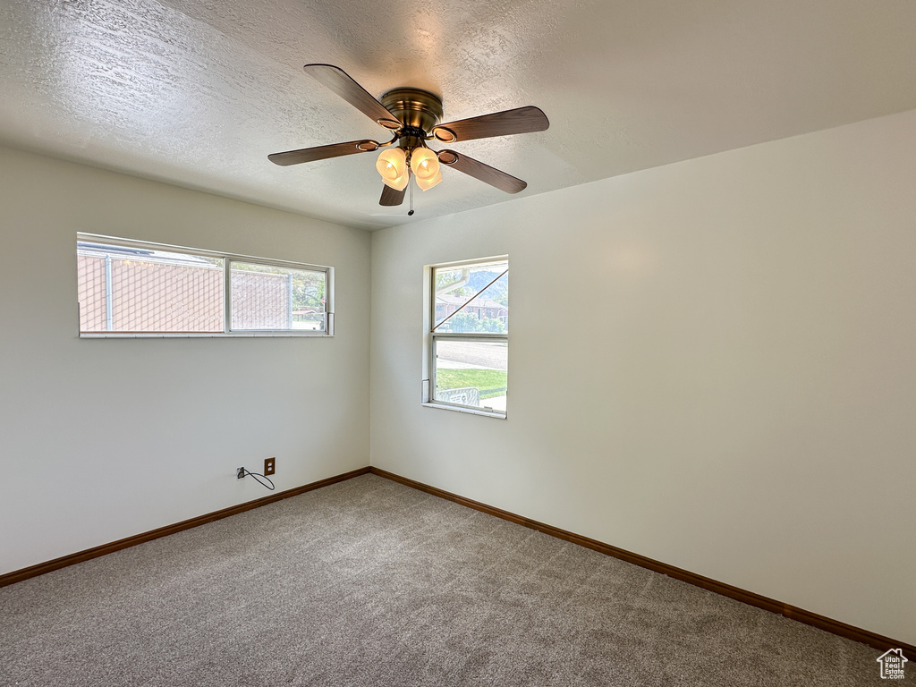Spare room with ceiling fan, carpet, and a textured ceiling