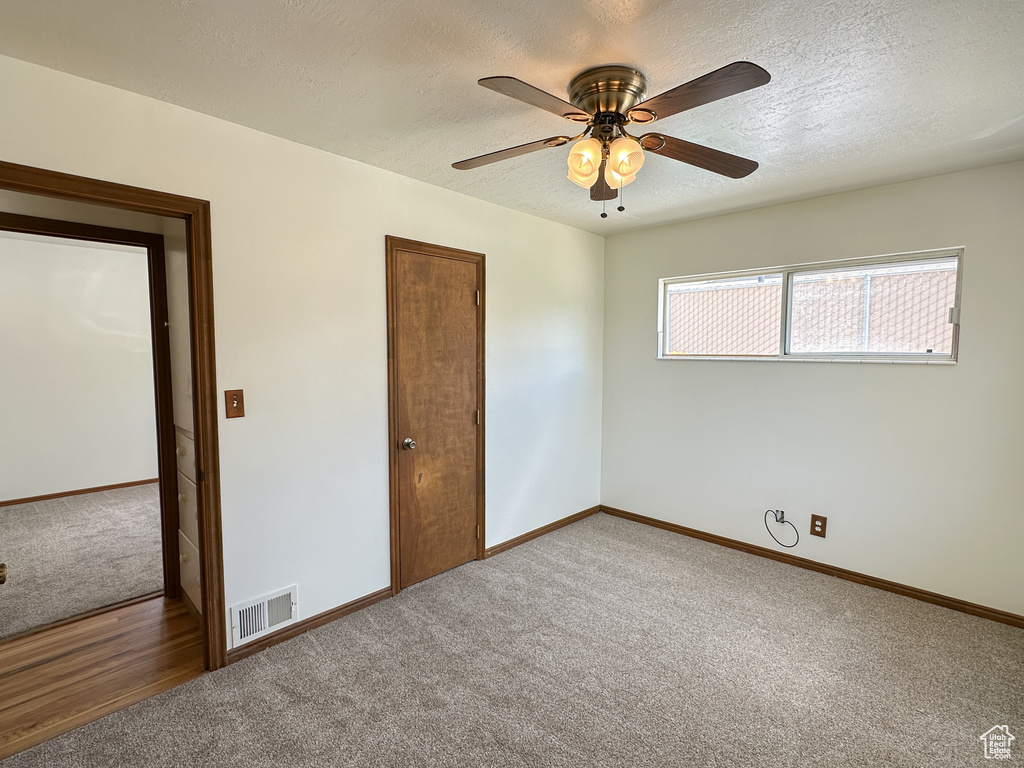 Unfurnished bedroom featuring ceiling fan, hardwood / wood-style flooring, and a textured ceiling