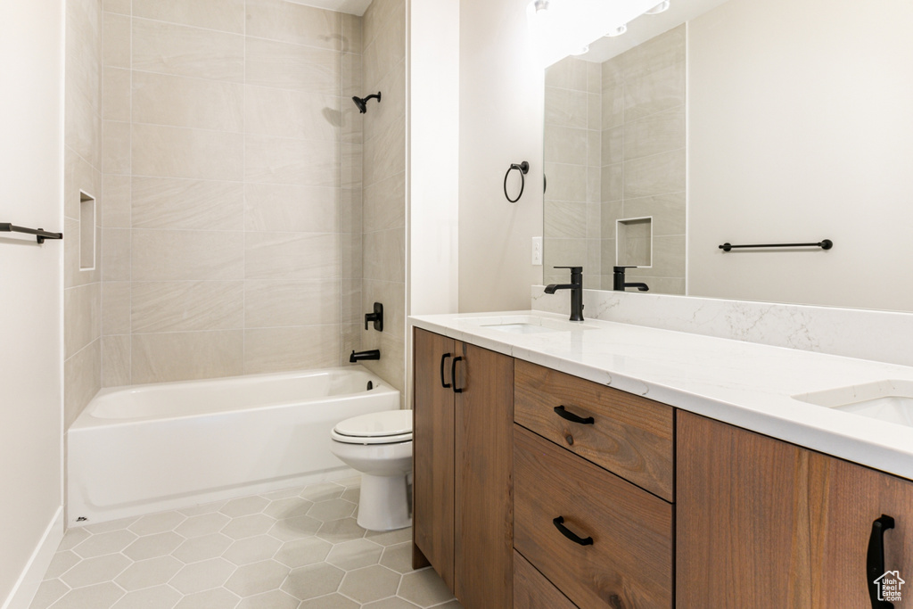 Full bathroom with tiled shower / bath combo, vanity, toilet, and tile flooring