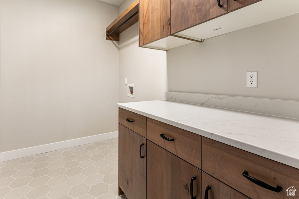 Washroom featuring cabinets, hookup for a washing machine, and light tile flooring