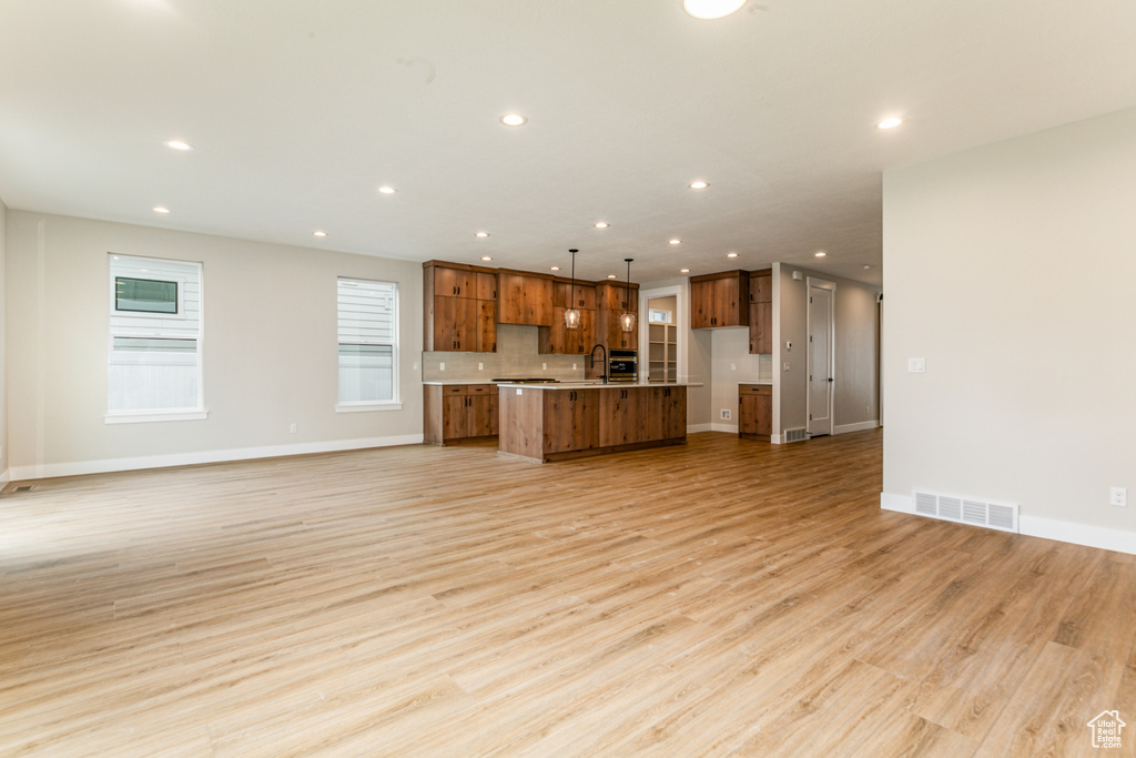Unfurnished living room featuring sink and light hardwood / wood-style floors