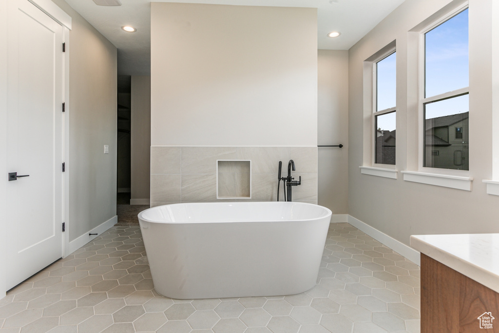 Bathroom with vanity, tile flooring, tile walls, and a tub