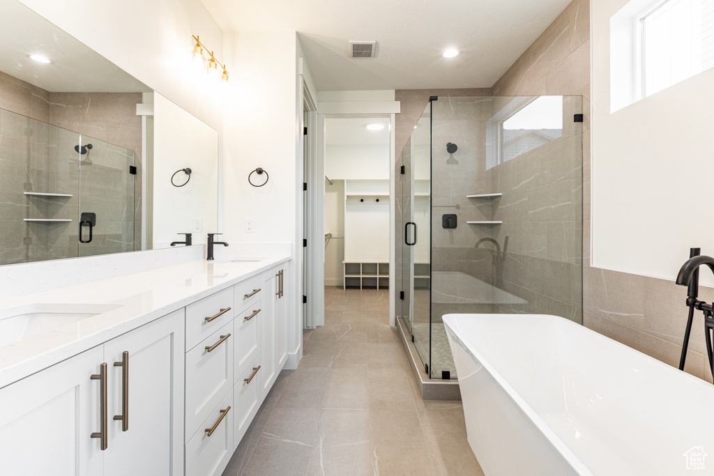 Bathroom featuring double vanity, shower with separate bathtub, and tile floors