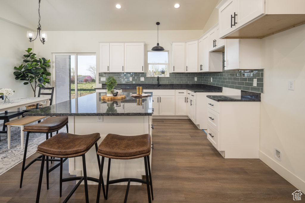 Kitchen featuring white cabinets, dark hardwood / wood-style flooring, a center island, and tasteful backsplash