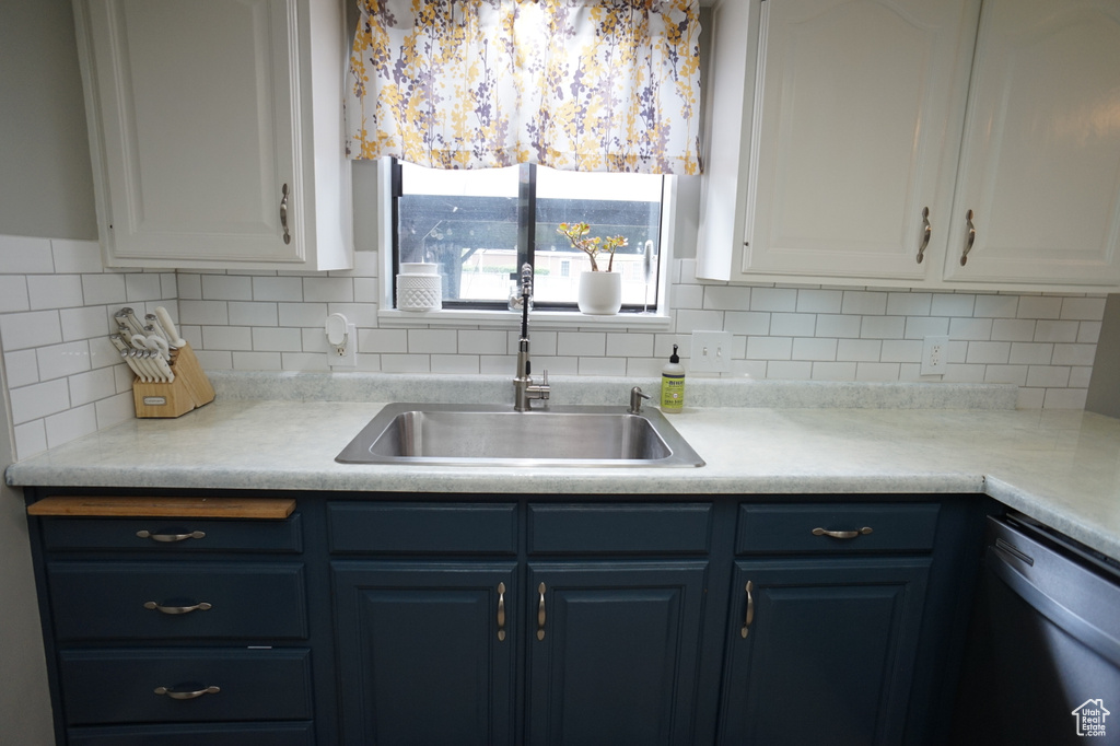 Kitchen with blue cabinetry, dishwasher, tasteful backsplash, white cabinetry, and sink