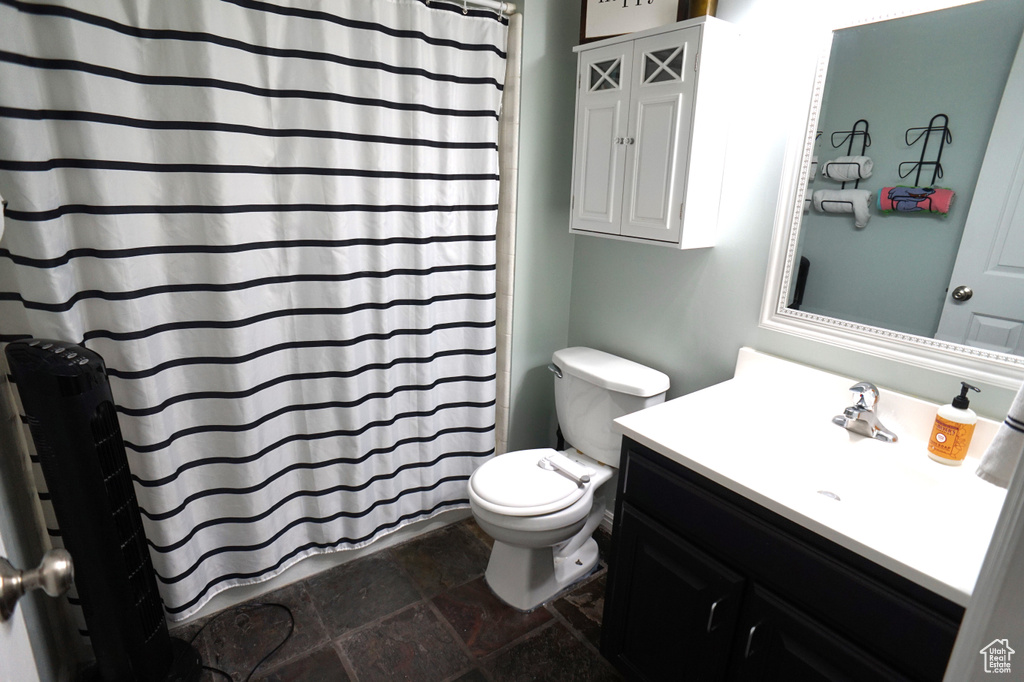 Bathroom featuring vanity with extensive cabinet space, toilet, and tile floors