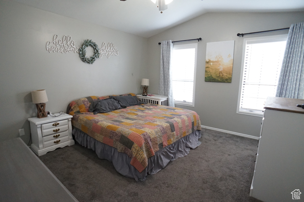 Bedroom with lofted ceiling, ceiling fan, and dark carpet