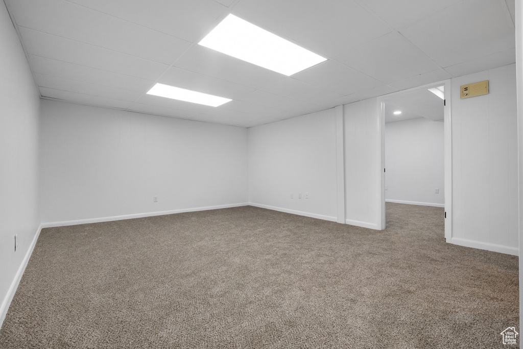 Basement with a paneled ceiling and carpet flooring
